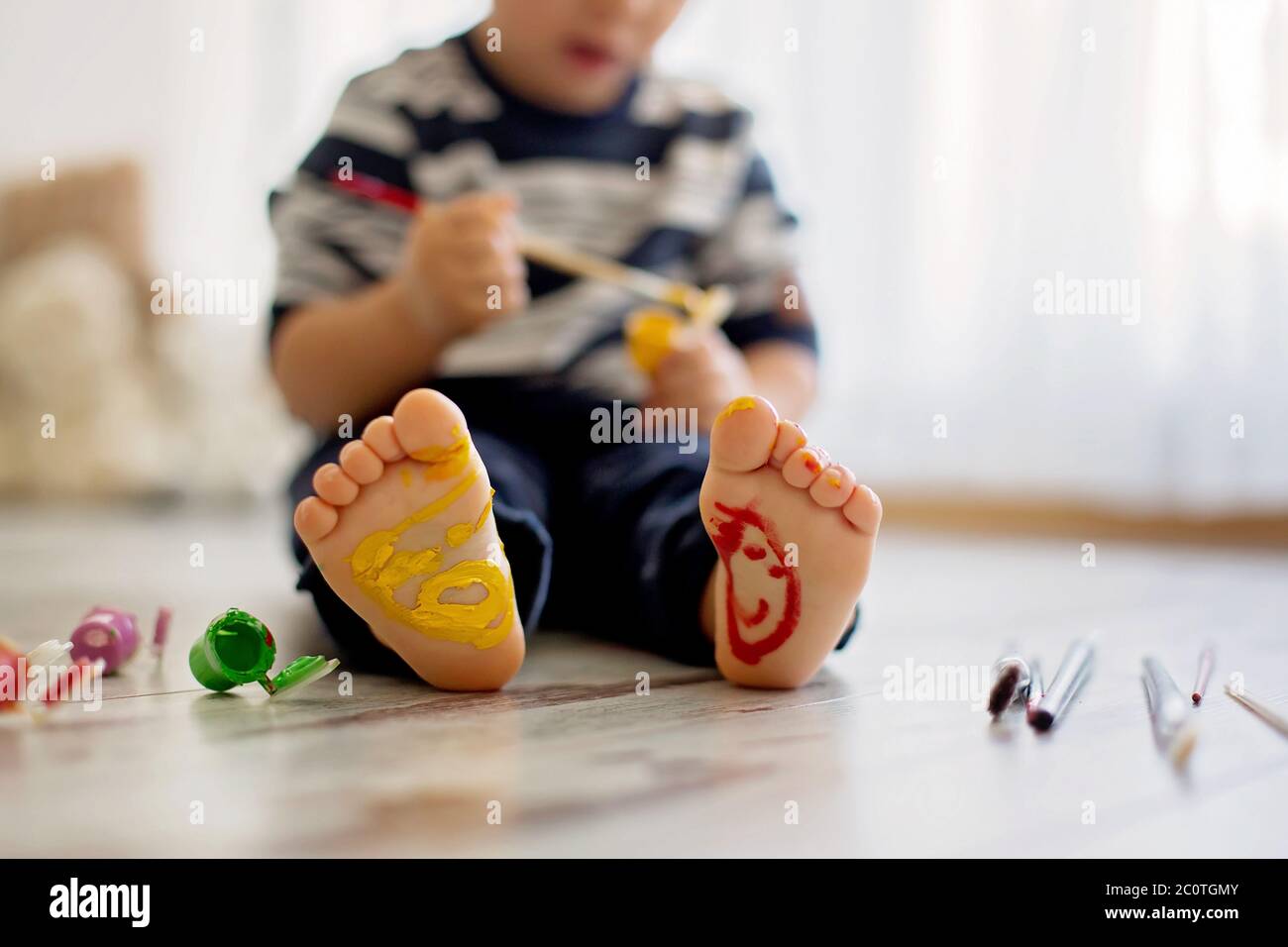 Brothers, playing at home, painting on their feet, tickling, laughing and smiling Stock Photo