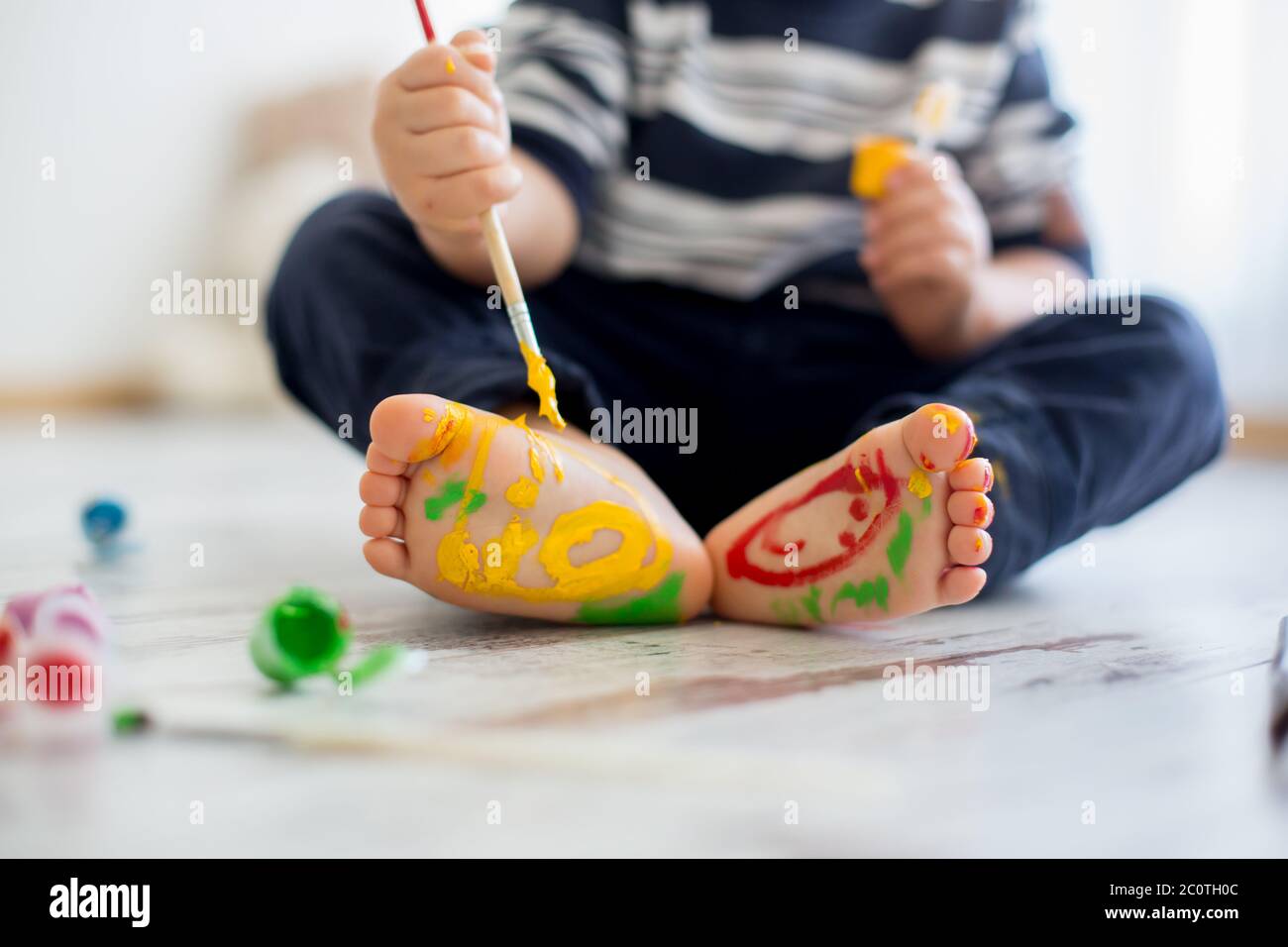 Brothers, playing at home, painting on their feet, tickling, laughing and smiling Stock Photo