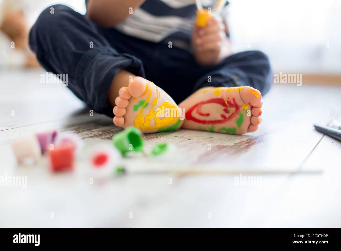 Brothers, playing at home, painting on their feet, tickling, laughing and smiling Stock Photo