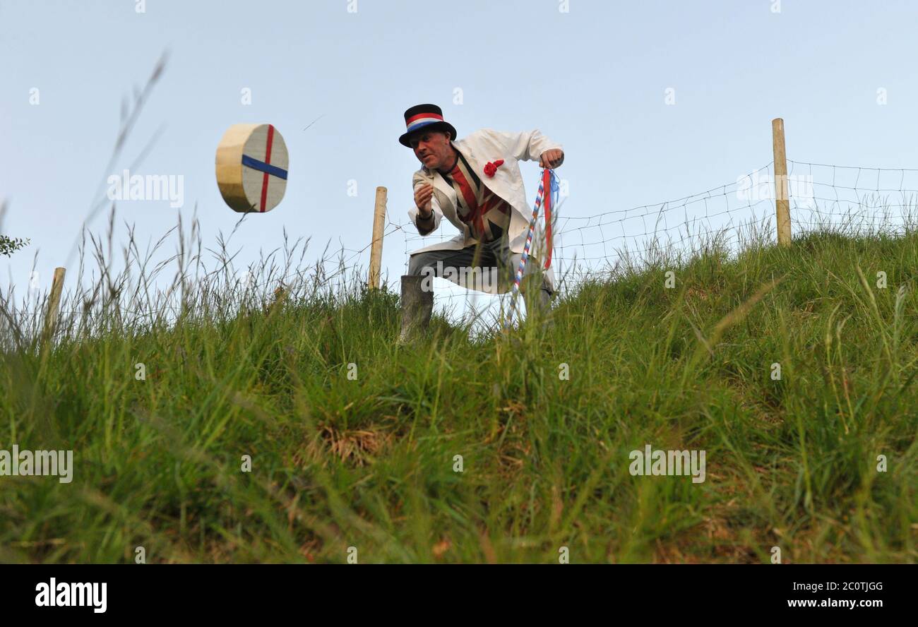 The Cheese Rolling Master of Ceremonies Jem Wakeman rolls the ceremonial cheese down Cooper's Hill, Gloucestershire just before 5.30am Stock Photo