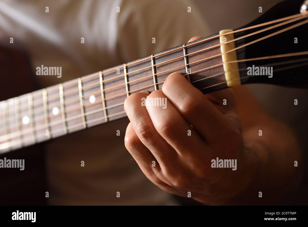 Acoustic guitar fingerboard detail and hands playing doing a D major chord Stock Photo