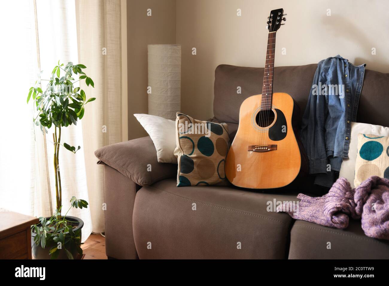 Room with an acoustic guitar on a sofa in a warm environment Stock Photo