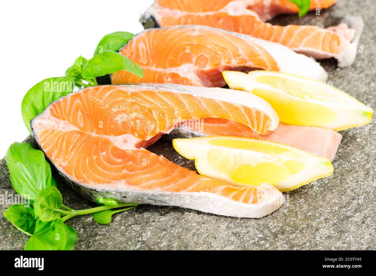 Salmon on stone with basil and lemon isolated on white Stock Photo