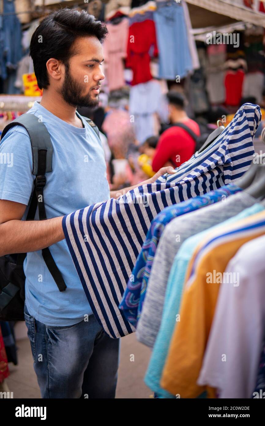 Indian young man looking and buying clothing from outdoor street market