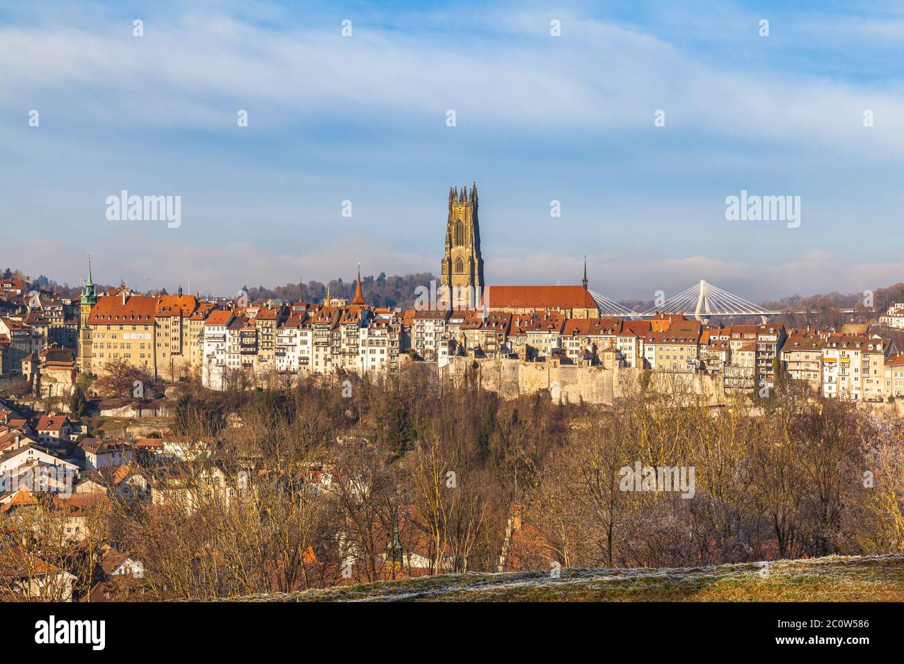 Stunning panorama view of Fribourg (Freiburg) old town skyline with Fribourg Cathedral in middle from Chapelle St. Jost on sunny winter day with blue Stock Photo