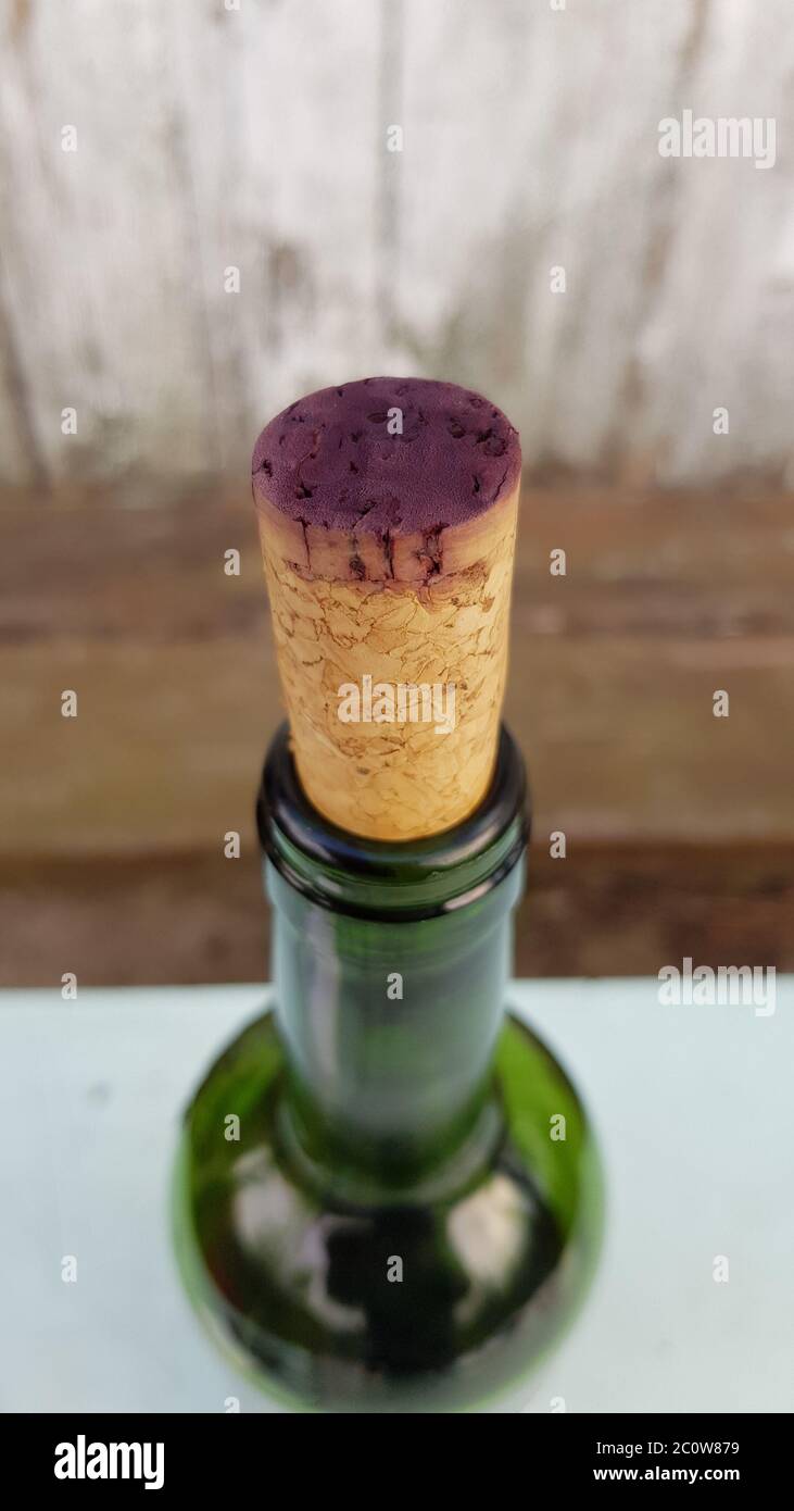 Closeup to purple surface of old wine cork colored by grape wine. Top of wine bottle on blur rustic wooden background with copy space Stock Photo