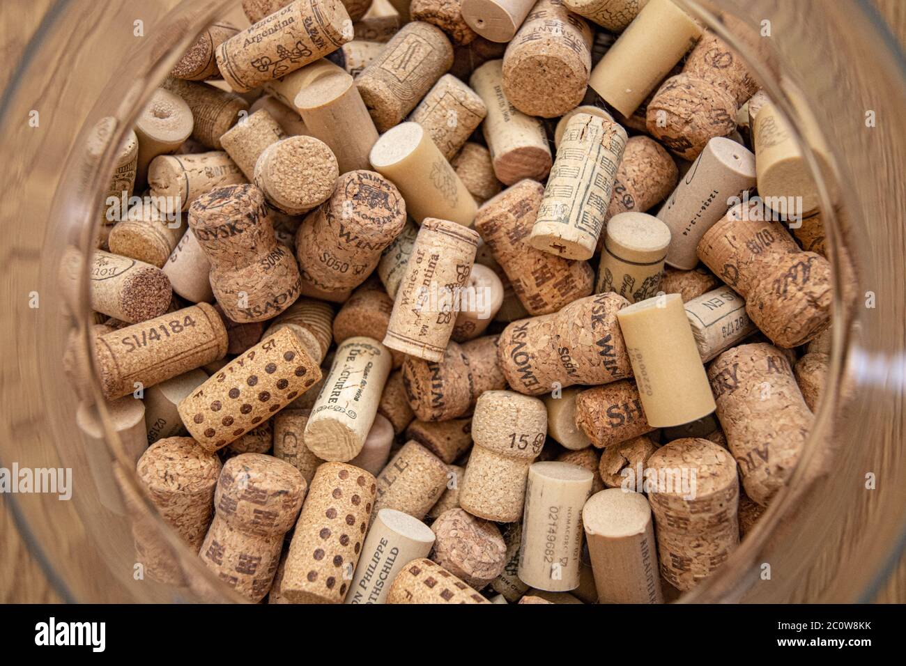Top view of round glass vase neck with used wine cork stoppers inside. Pile of various wine bottle corks for winery background Stock Photo
