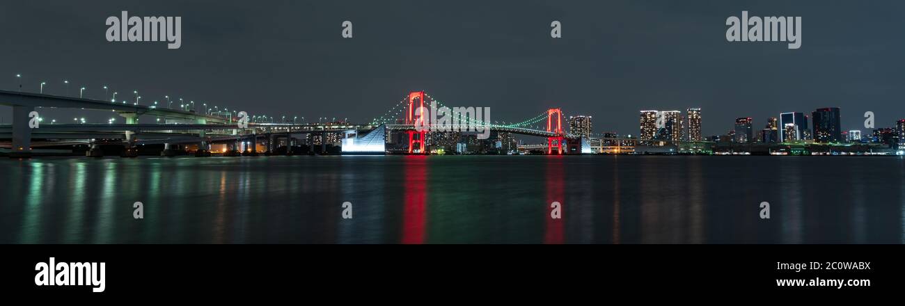 Panoramic nightview of Rainbow Bridge, illuminated in red as a sign of 'Tokyo Alert (coronavirus alert for Tokyo area)' in Odaiba, Japan. Stock Photo