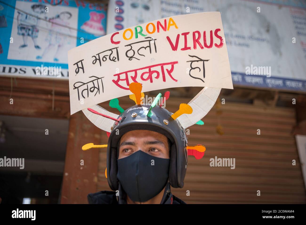 A protester wearing a helmet imitating the coronavirus structure with placard on it during the demonstration. Nepalese people have gathered to protest against the government's in-efficiency handling the coronavirus pandemic crisis
