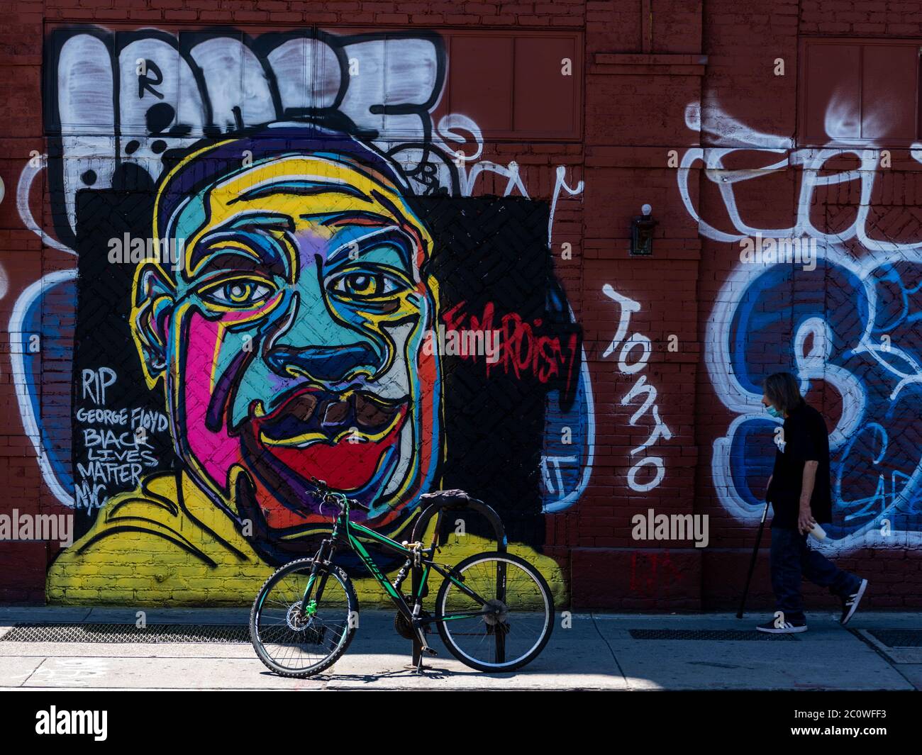 New York, New York, USA. 12th June, 2020. New York, New York, U.S.: a man walks past a George Floyd mural painted by street artist Fumero in East Village during the peaceful protests opposing systemic racism and police brutality. Credit: Corine Sciboz/ZUMA Wire/Alamy Live News Stock Photo