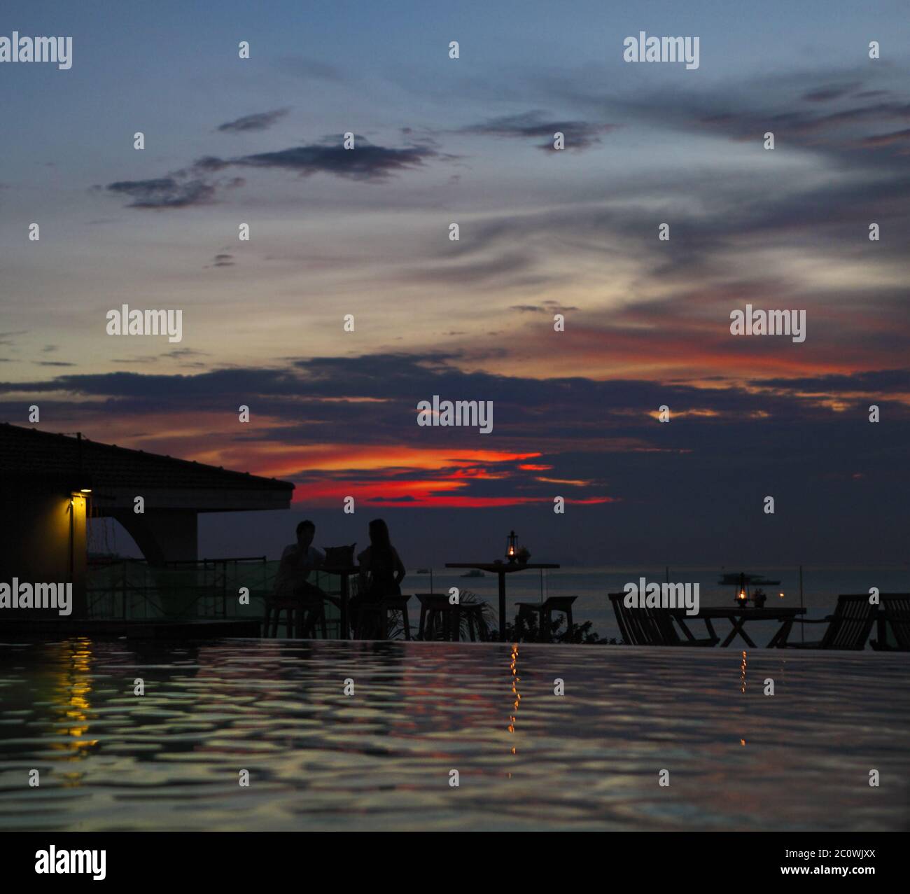 The silhouette of couple watching sunset on the beach Stock Photo - Alamy