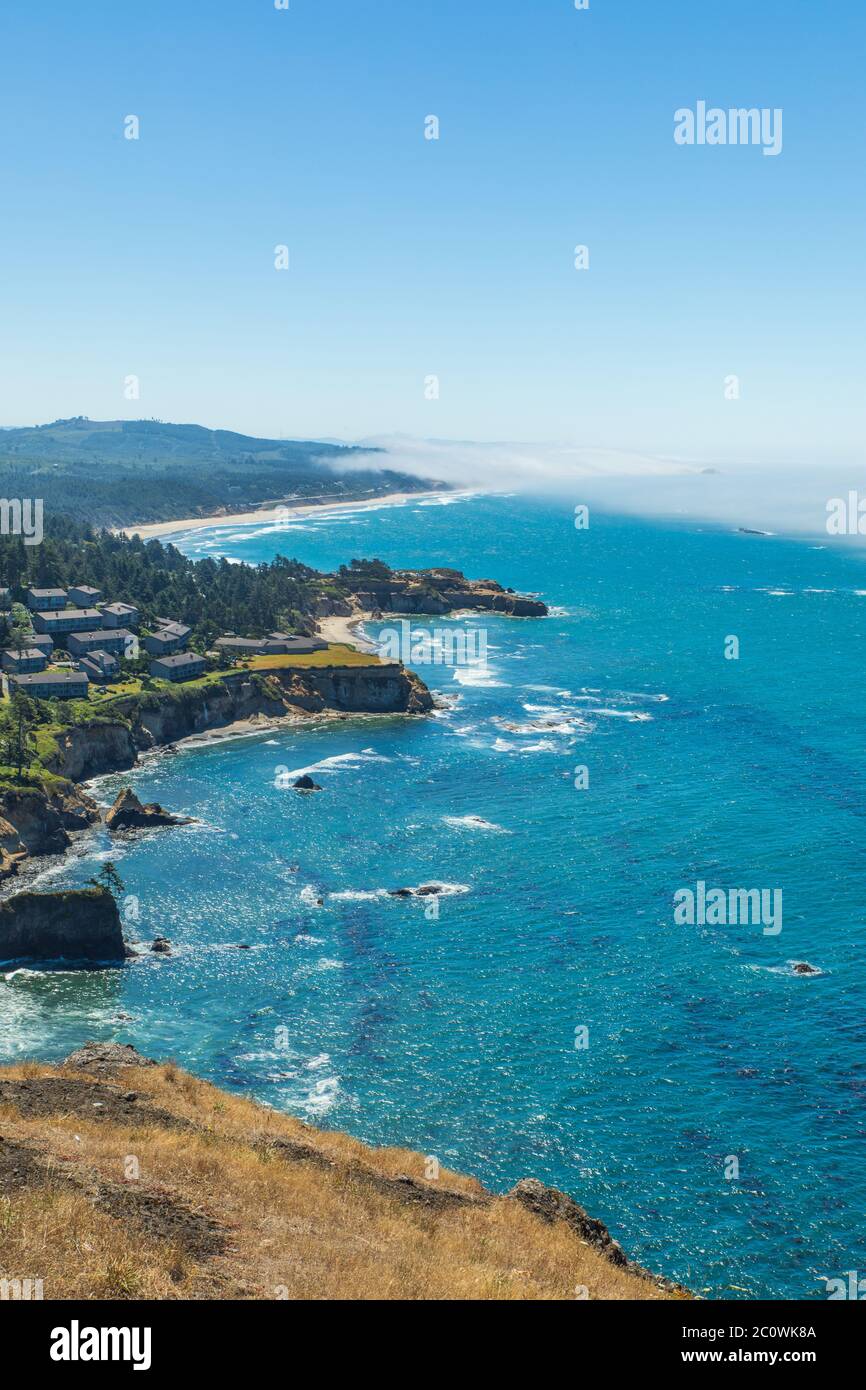 Vertical photo - Looking down at the rugged coastline with fog in the distance over the water from Cape Foulweather overlook in Oregon Stock Photo