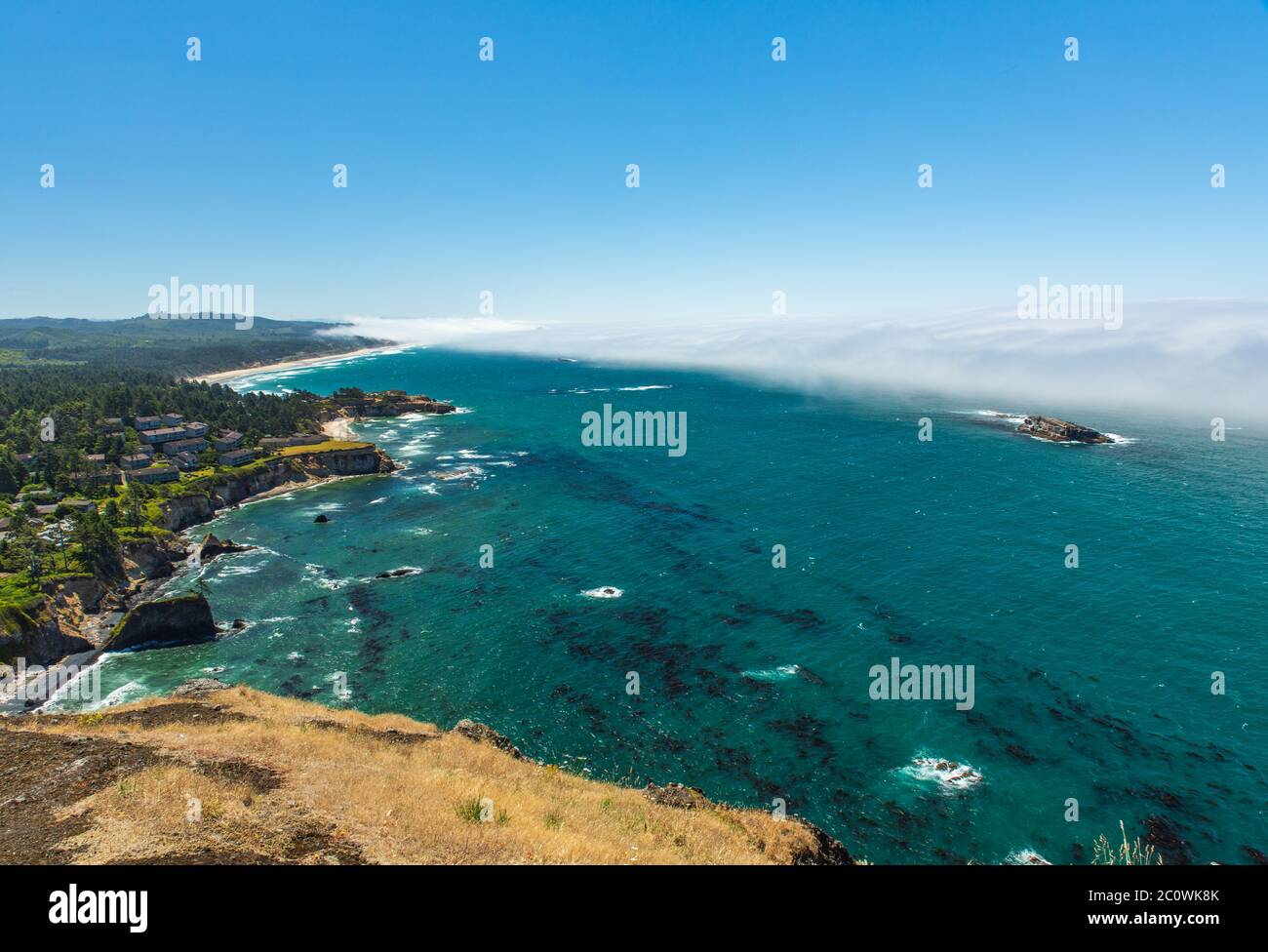 Scenic view from Cape Foulweather overlook of fog rolling in from the ocean toward the rugged coast in Oregon Stock Photo