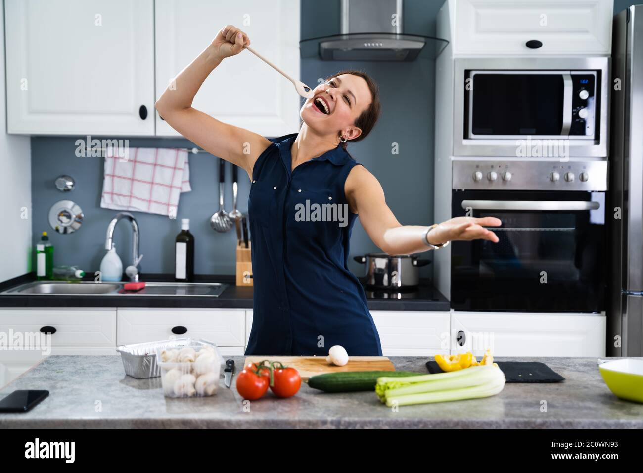 Woman Dancing And Singing While Cooking In Kitchen Stock Photo Alamy