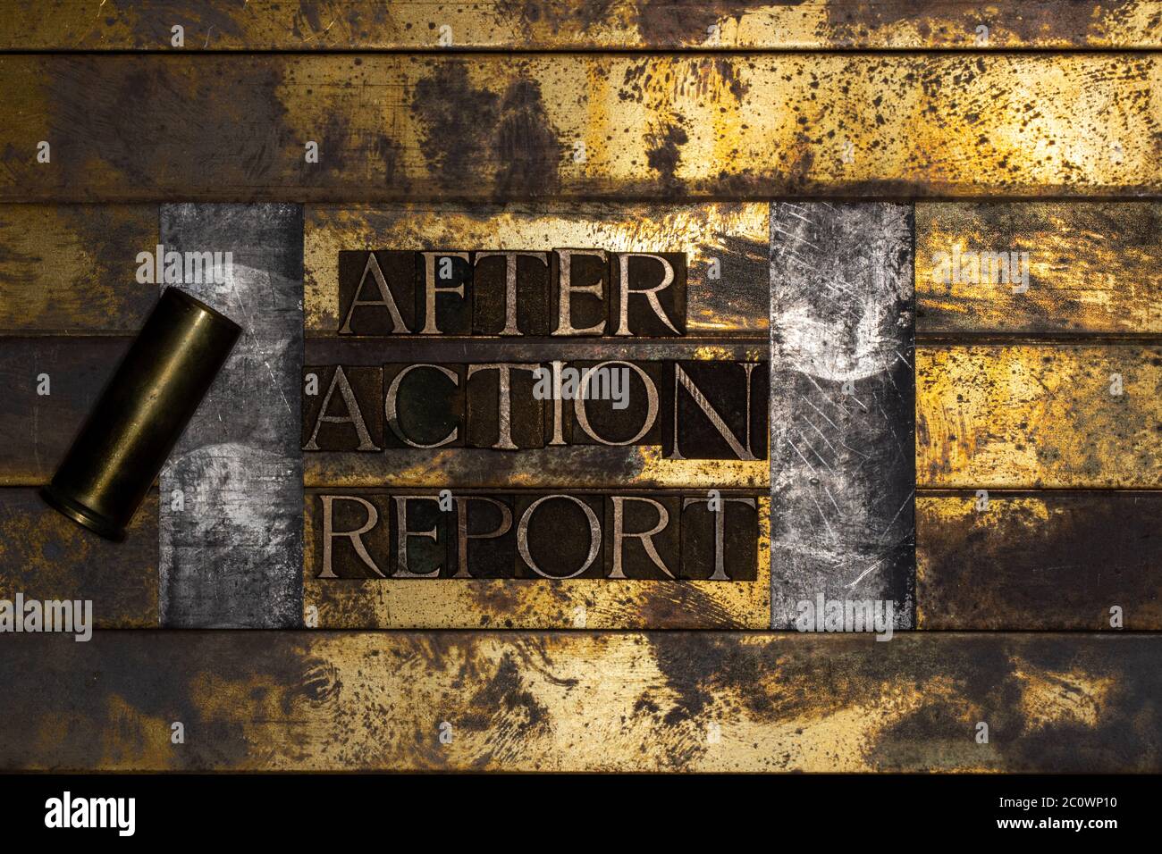 Photo of real authentic typeset letters forming After Action Report text with bullet casing on vintage textured silver grunge copper and gold Stock Photo