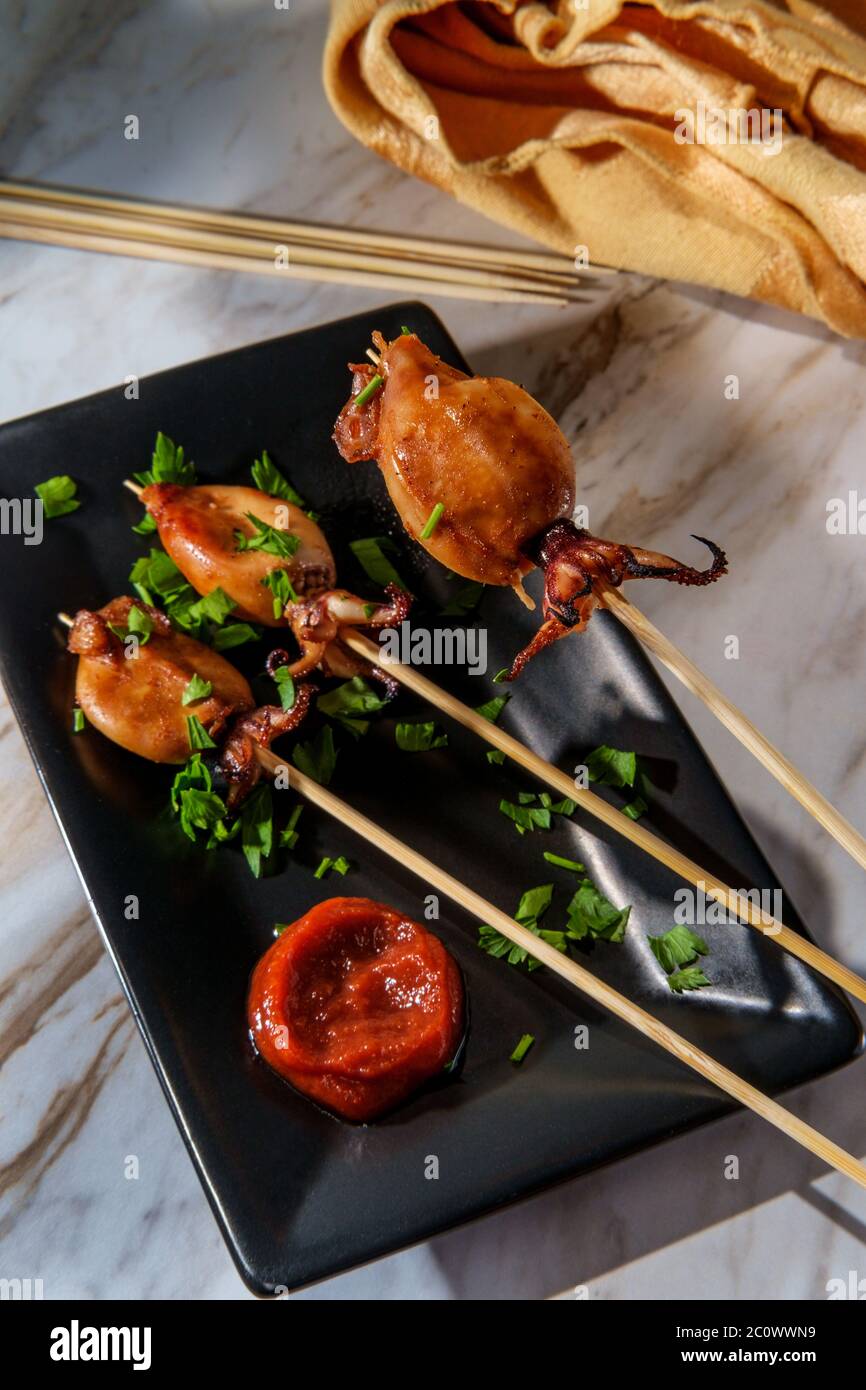Seafood grilled squid satay kebab skewers with tentacles and sriracha