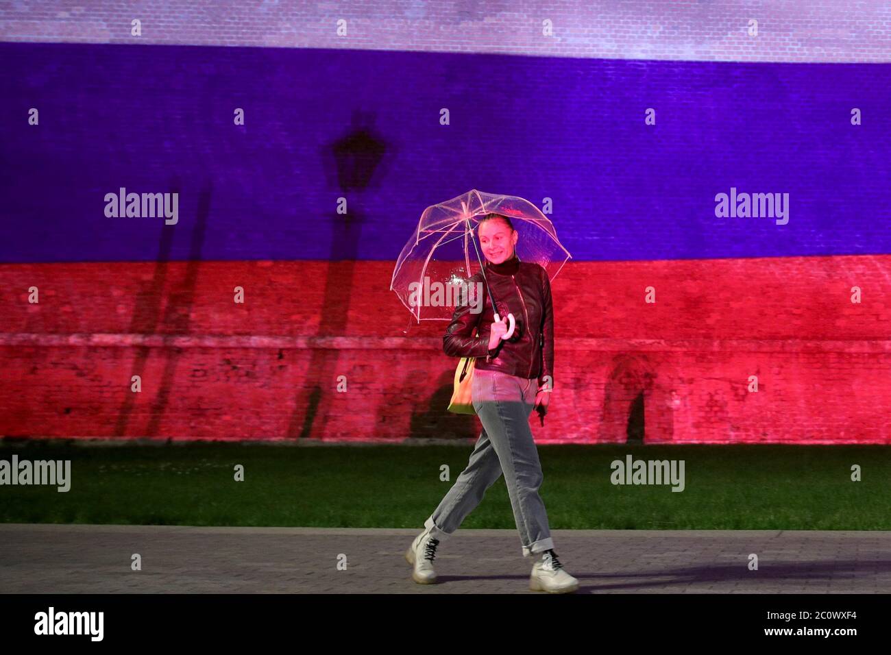 Moscow Russia June 12 A Woman Holding An Umbrella Walks As A Light Show In The Russian National Colours Is Projected Onto The Kremlin Wall During A National Holiday Known