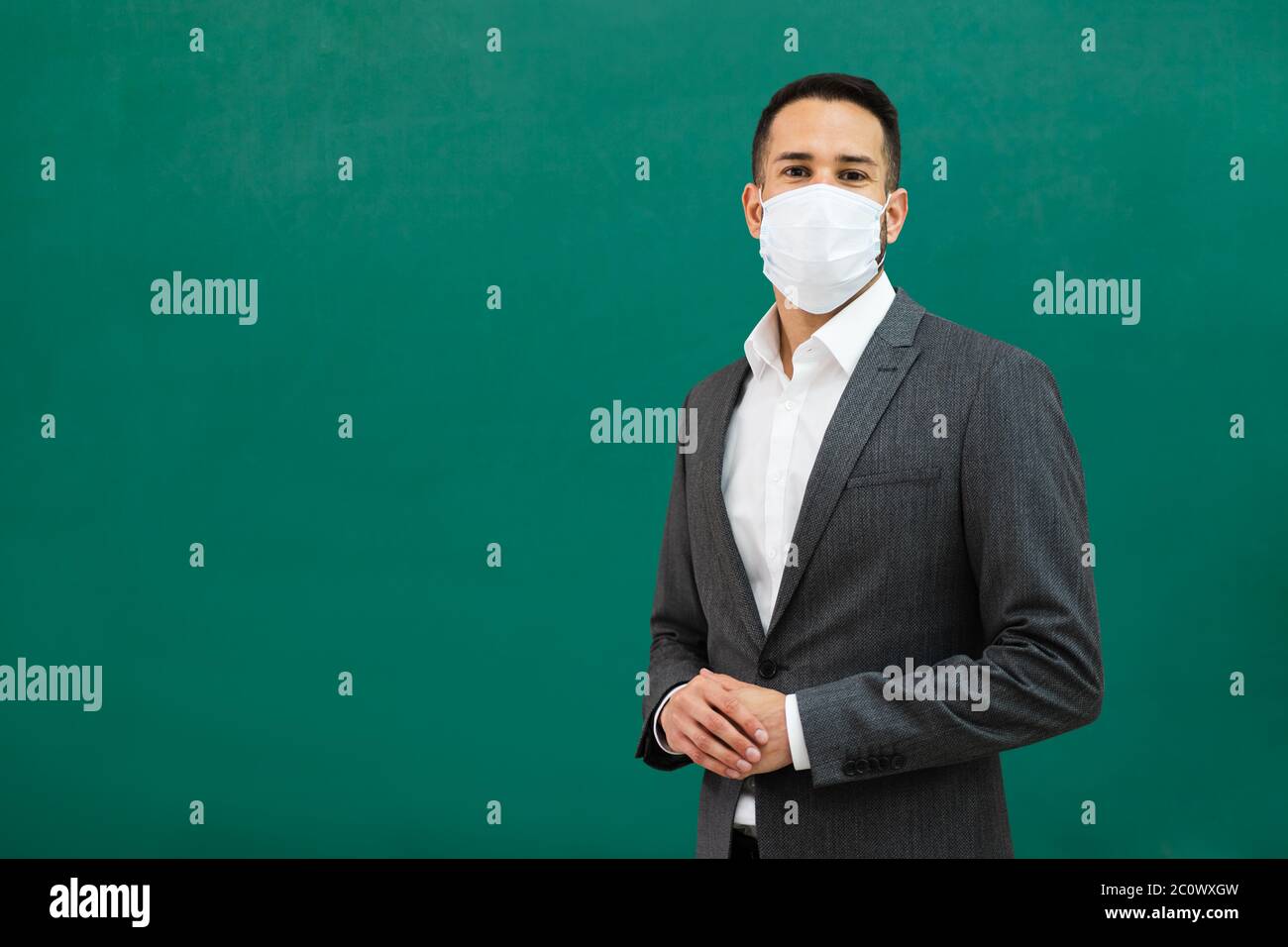 School Teacher Standing In Class Wearing Face Mask Stock Photo
