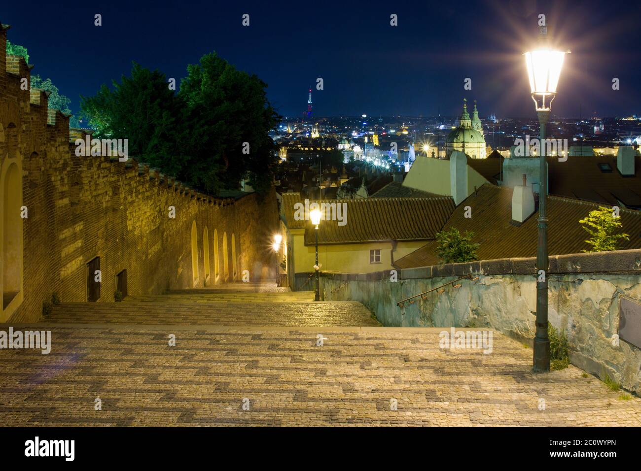 New castle stairs road leading up to Prague Castle Czech Republic enlightened by street lamps with a beautiful view over Prague during night Stock Photo