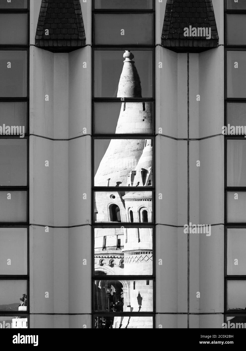 Detailed view of warped reflection of Fisherman's Bastion, aka Halaszbastya, fairy tale towers in windows of modern hotel. Architectural constrast of historical landmark and hated modern architecture of communistic Hungary. Budapest, capital city of Hungary, Europe. UNESCO World Heritage Site. Black and white image. Stock Photo