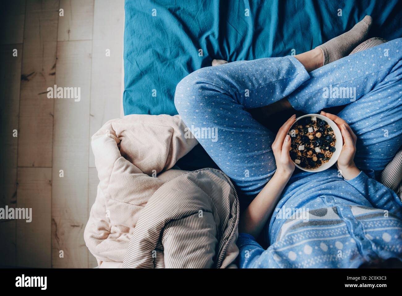 Upper view photo of a woman wearing pajama with healthy habits eating cereals Stock Photo