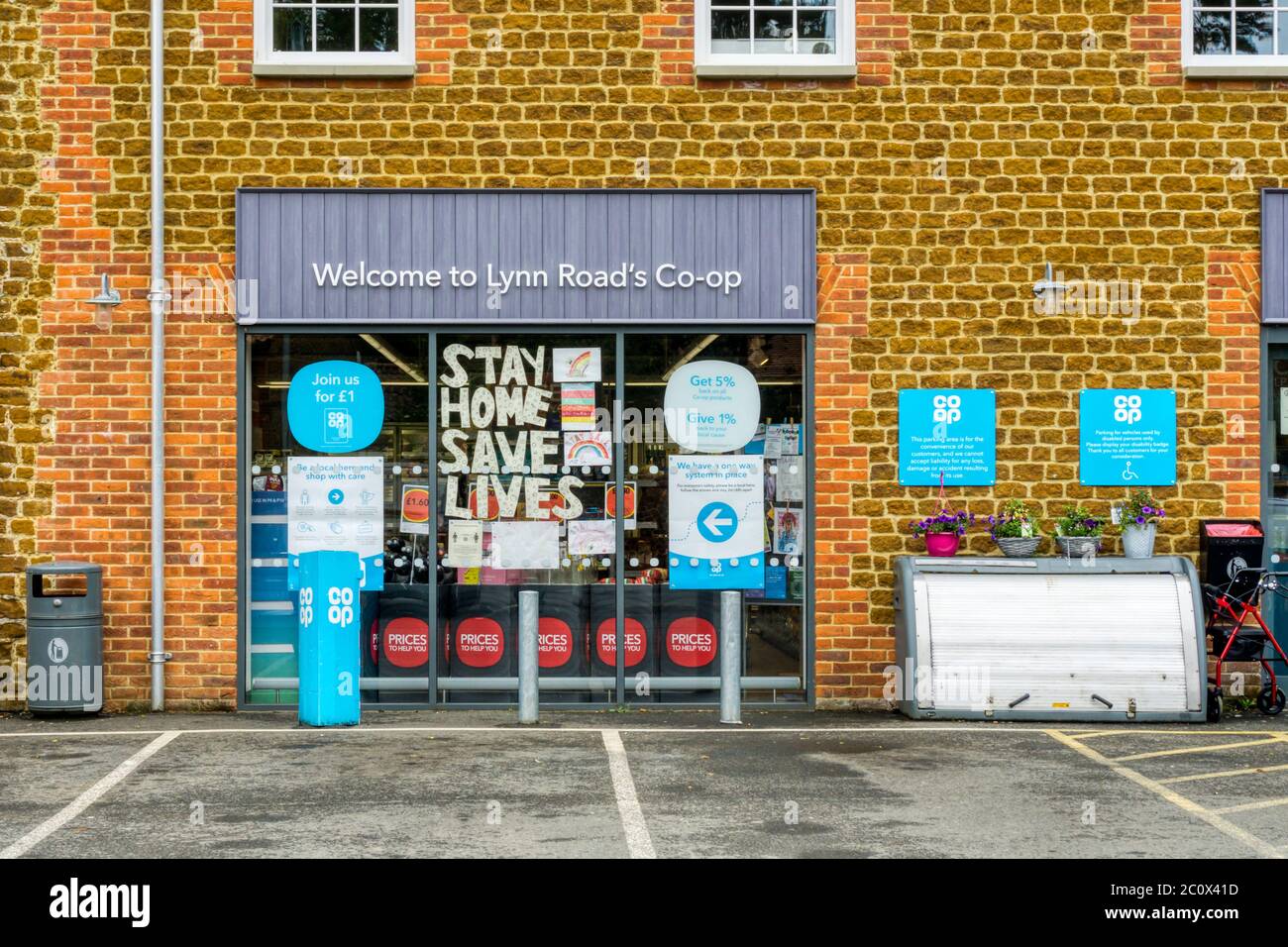 Stay Home Save Lives sign in window of a local Co-Op during 2020 COVID-19 coronavirus pandemic. Stock Photo