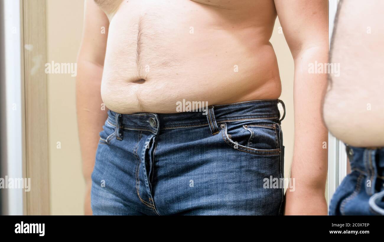 Big fat male belly hanging over small jeans. Concept of male