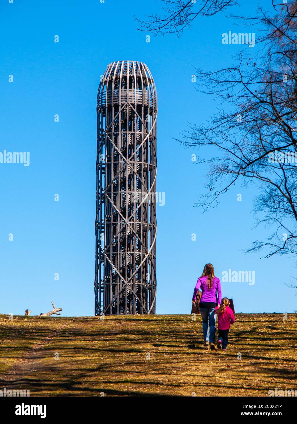 Young woman with doughter walks toward wooden lookout tower in Hermanice, Czech Republic. Stock Photo