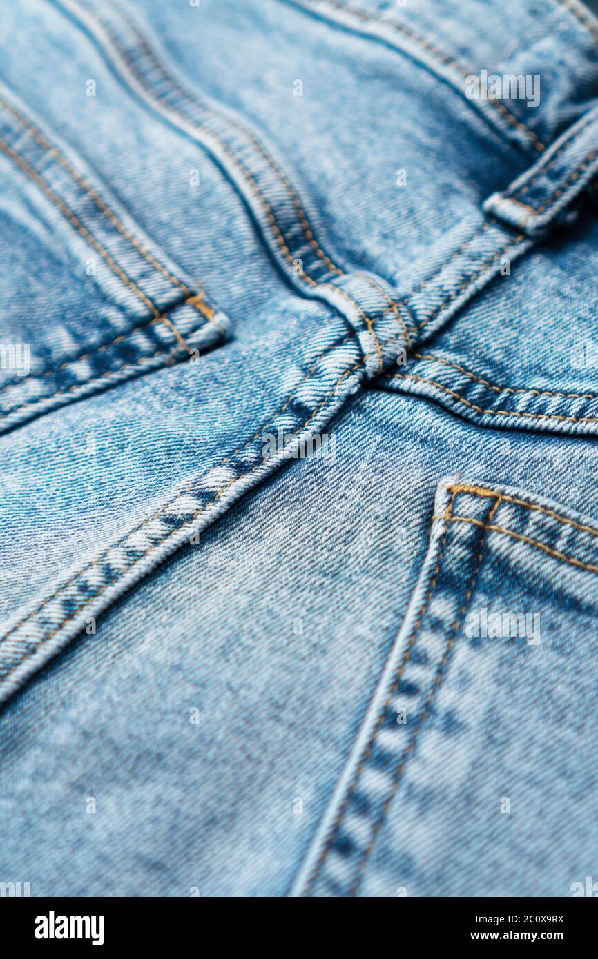 Close-up of denim blue fabric with pockets and yellow seams. Fashionable jeans. Front view. Stock Photo