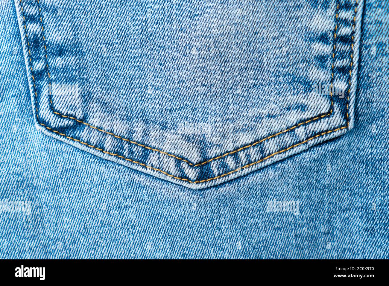 Close-up pocket of denim blue fabric with yellow seams. Fashionable jeans. View from above. Stock Photo