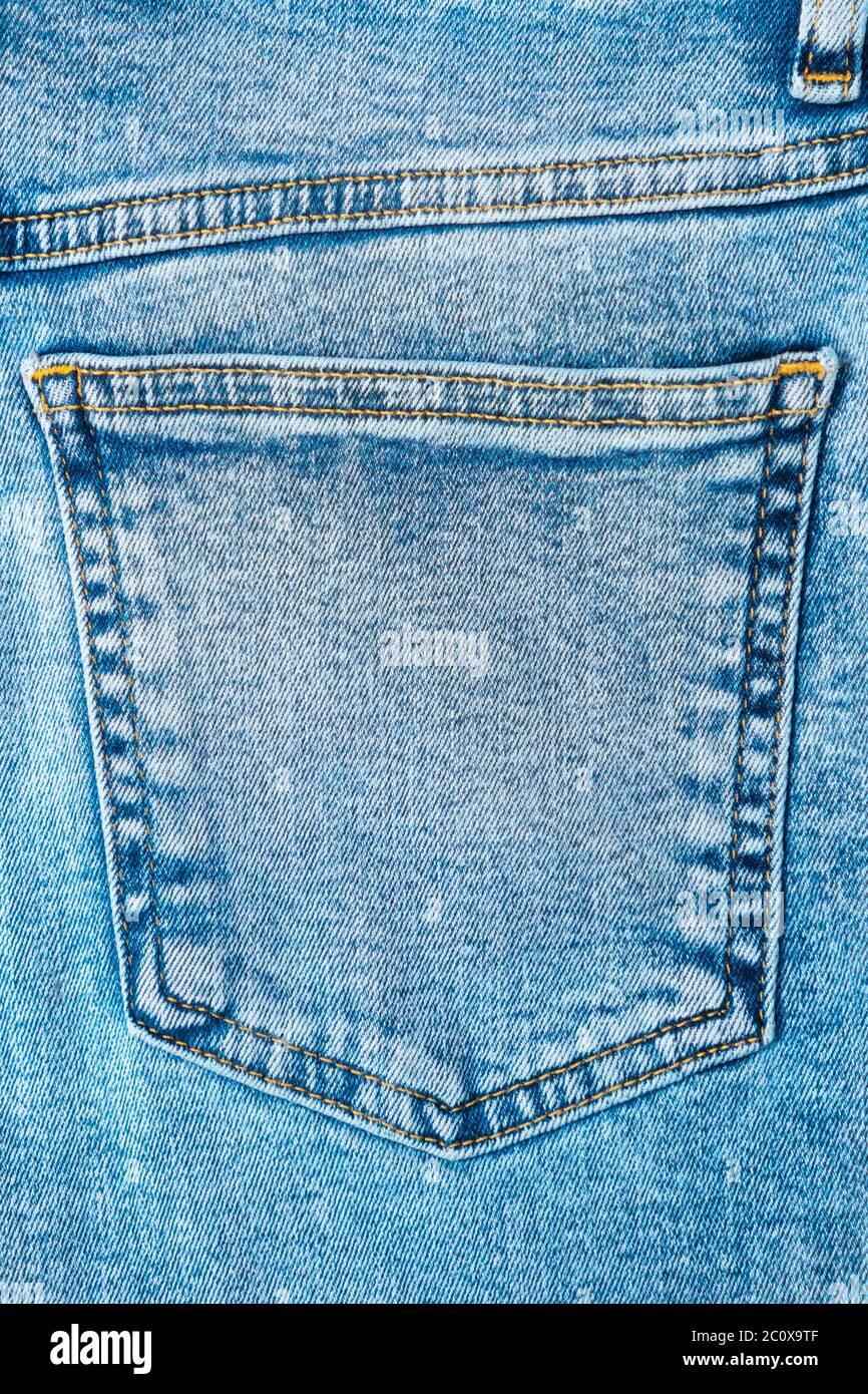 Close-up pocket of denim blue fabric with yellow seams. Fashionable rough jeans. Vertical Top View. Stock Photo