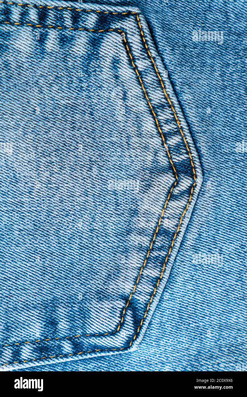 Close-up pocket of denim blue fabric with yellow seams. Fashionable jeans. Vertical Top View. Stock Photo