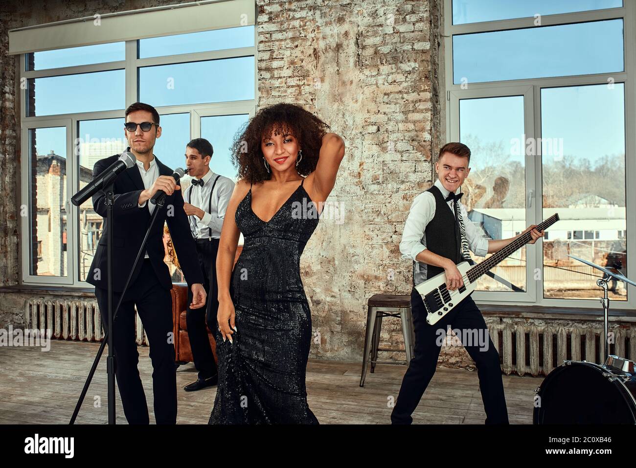Photo of a lot of ethnic musical group in studio. Musicians and an African American woman soloist posing on camera, during a rehearsal, loft Stock Photo