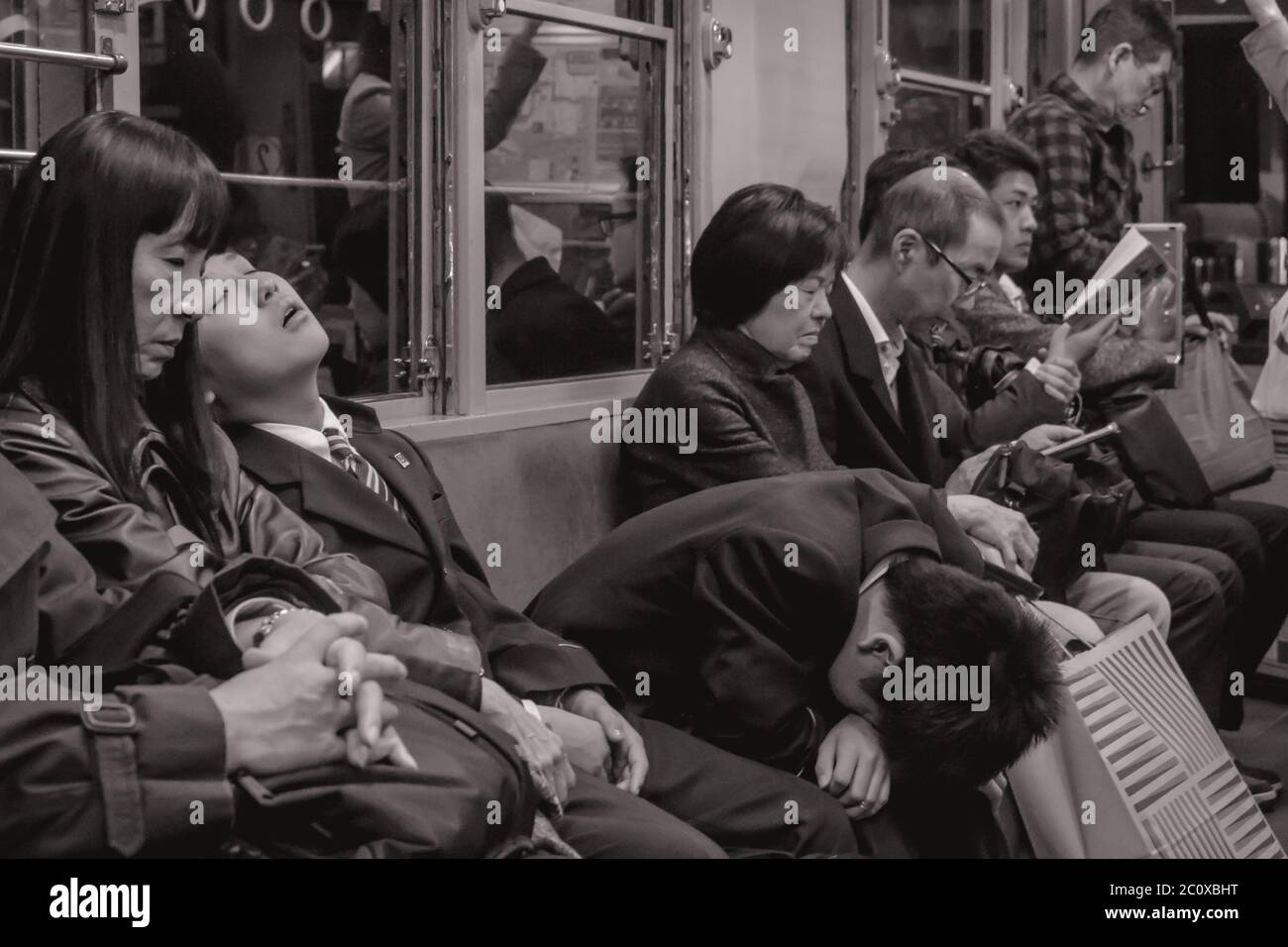 Passengers tired of work sleeping on a late night train in Hiroshima Japan Stock Photo