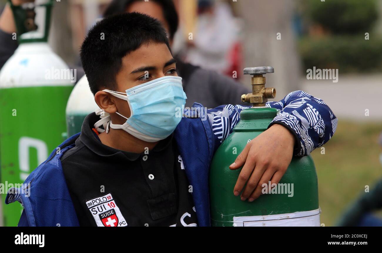 12 June 2020, Peru, Lima: A young man with a mouth guard is standing in line next to an oxygen bottle to refill it. Some Peruvians buy oxygen for relatives who are infected with Covid-19 and are treated at home. Others need the oxygen in the midst of the corona pandemic for relatives who suffer from other diseases. In the second most affected country in South America by the corona pandemic, the government wants to increase oxygen production. Funds would also be made available for the import of oxygen. 'We regard oxygen as an element of national interest,' said Defence Minister Martos the other Stock Photo