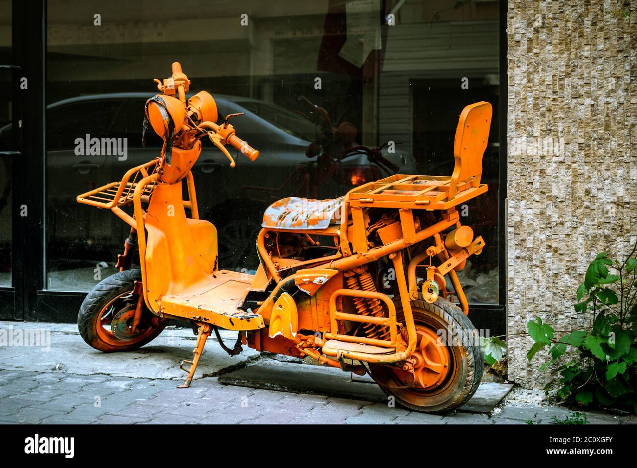 Turist anspore Mathis very shabby diy modified scooter, retro city bike, painted all orange,  phosphorous, stays as an offbeat object on the side of street Stock Photo -  Alamy
