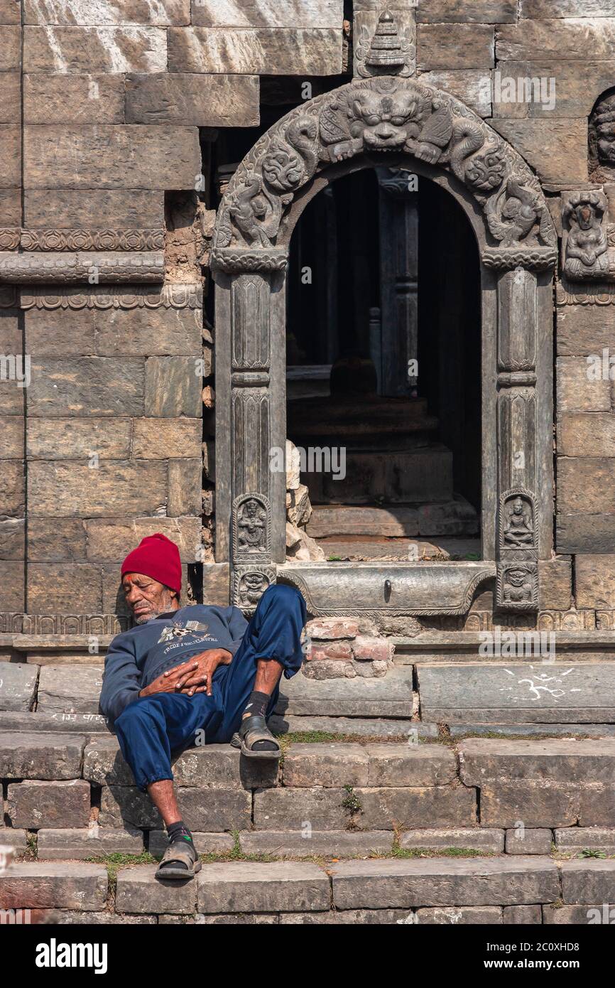 homeless man sleeping near temple entrance Stock Photo
