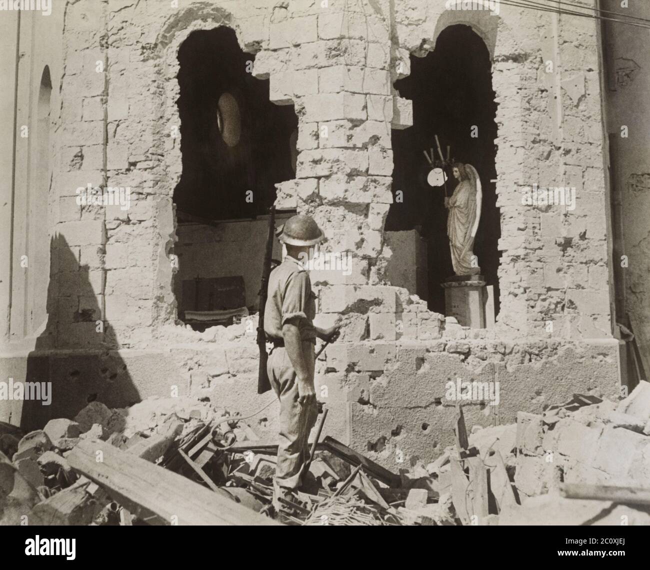 British Soldier standing in Rubble looking through Gaping Holes in Damaged Catholic Church, Tobruk, Libya, December 1941 Stock Photo