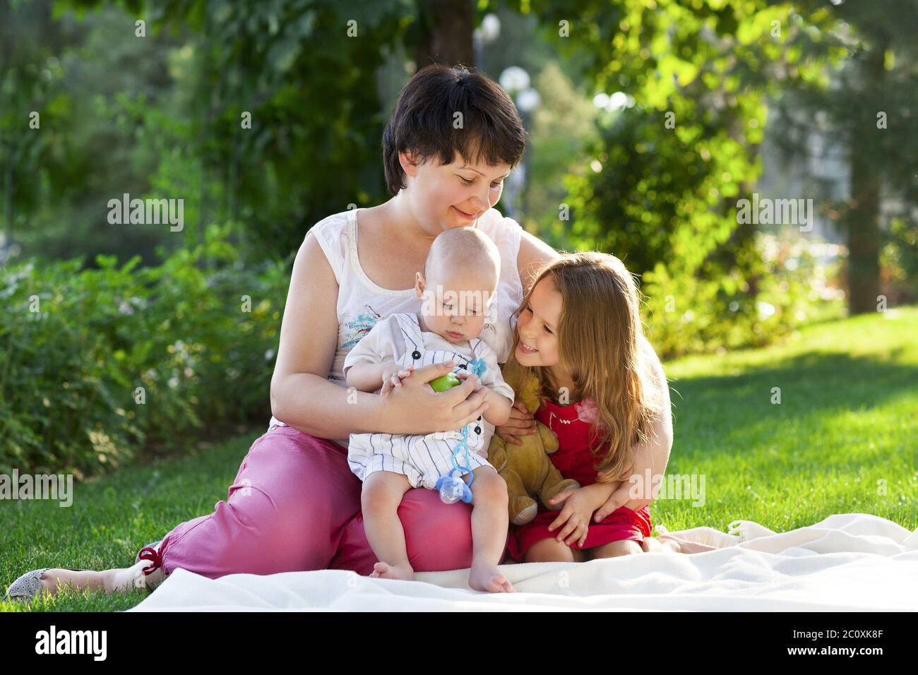 Mother and her kids outdoors. Happy mum and her children playing in park together Stock Photo