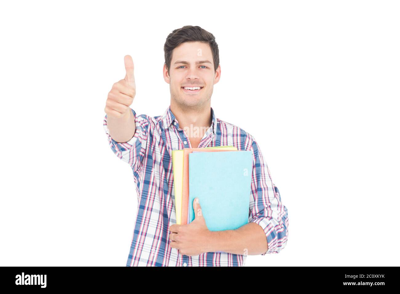 Portrait of smiling male student holding books and showing thumbs up ...
