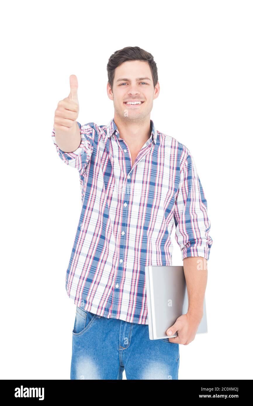 Portrait of smiling male student holding a laptop and showing a thumbs ...