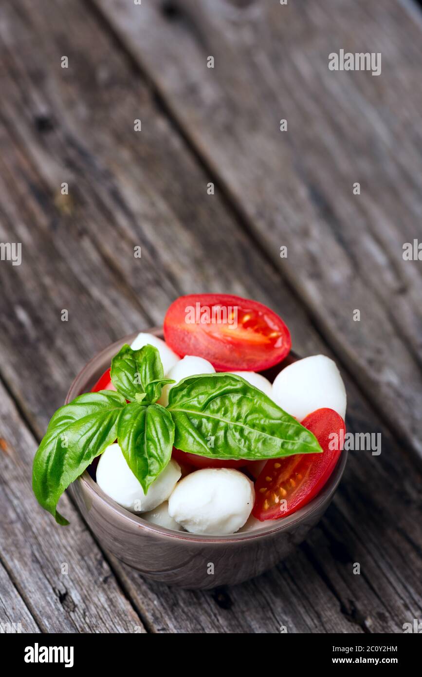 Tomato and mozzarella with basil leaves in bowl Stock Photo - Alamy