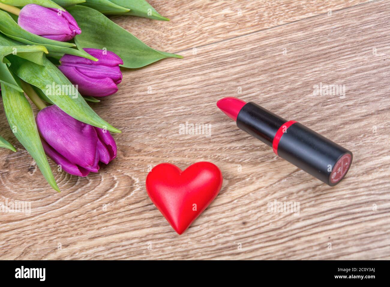 Lipstick, red heart and tulips on a wooden background Stock Photo