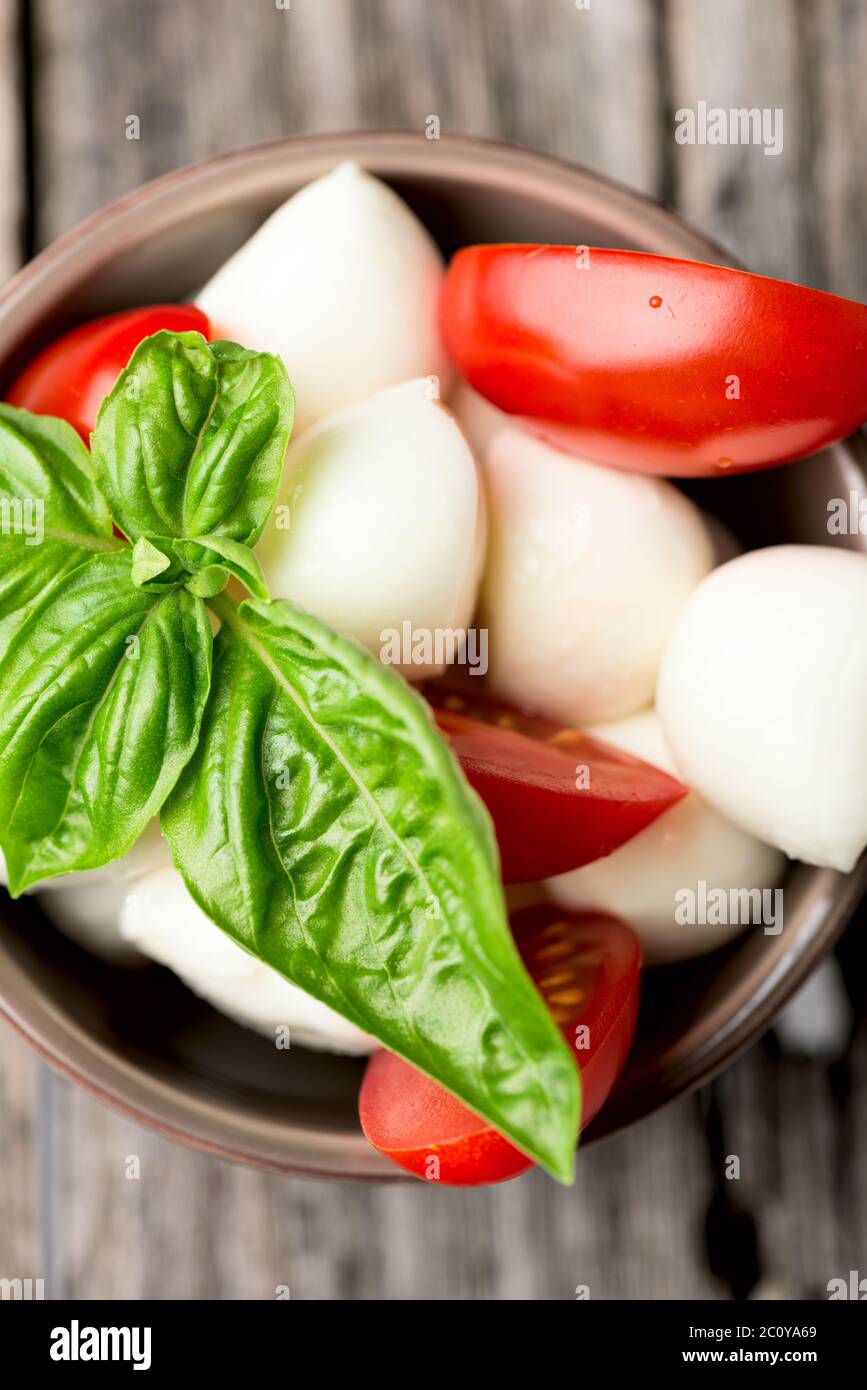 Tomato and mozzarella with basil leaves in bowl Stock Photo - Alamy