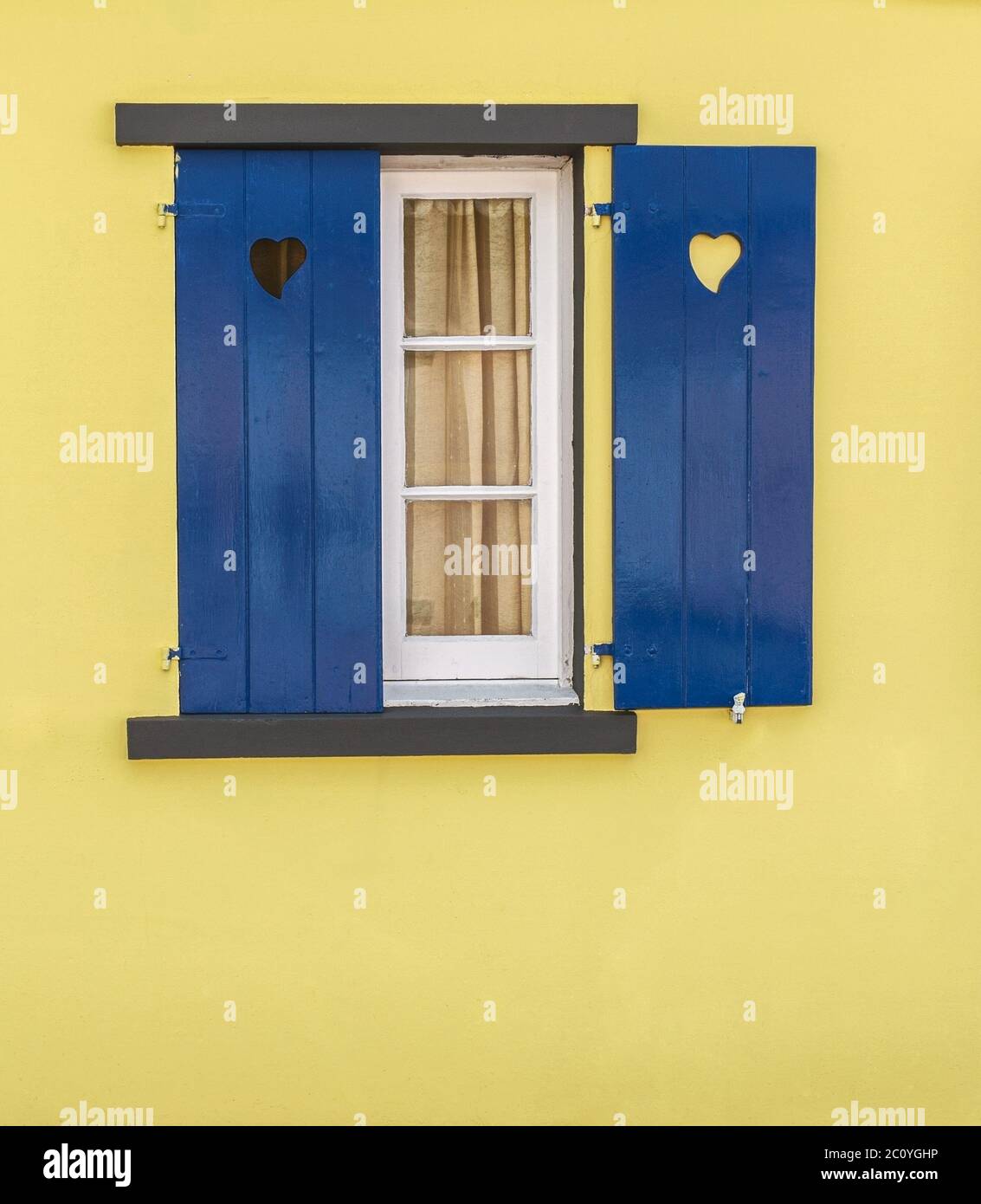 Detail of blue window with hearts and yellow wall Stock Photo