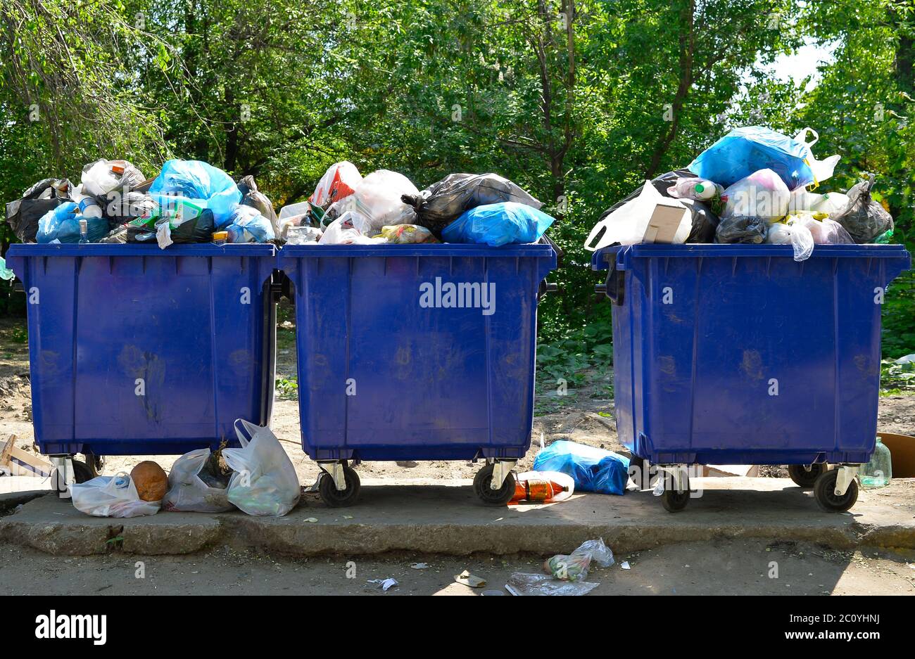 Overflowing garbage bins with household waste in the city. Stock Photo