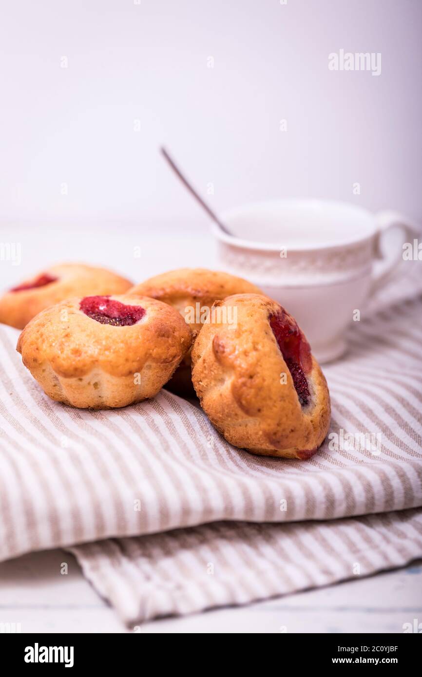 Tasty muffin cakes. Homemade buttercream cupcakes with strawberries on white wooden table. Stock Photo
