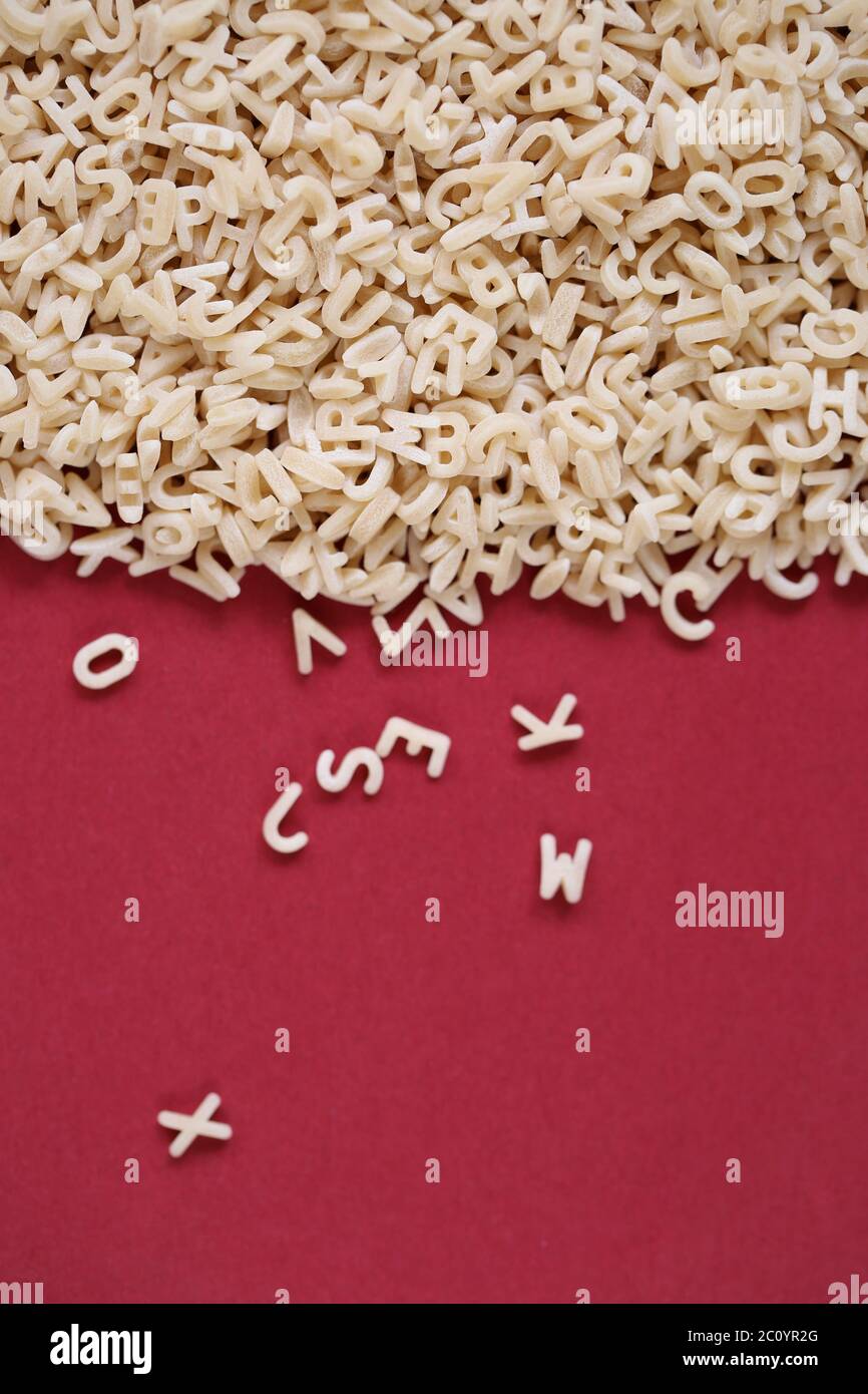 Pasta letters heap on a  burgundy background Stock Photo