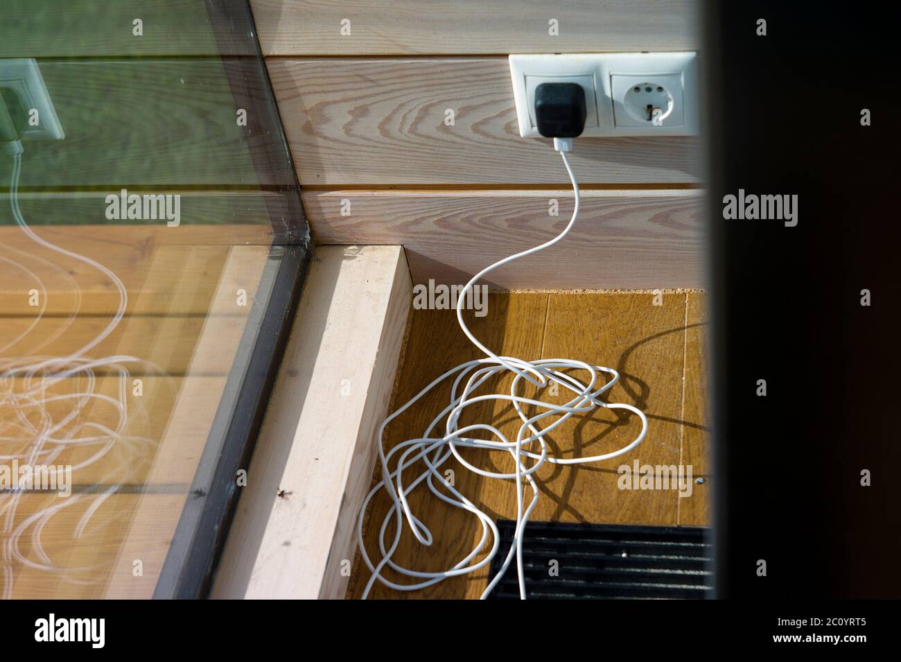 Tangled USB cable on the floor, plugged in electric socket, indoor ...
