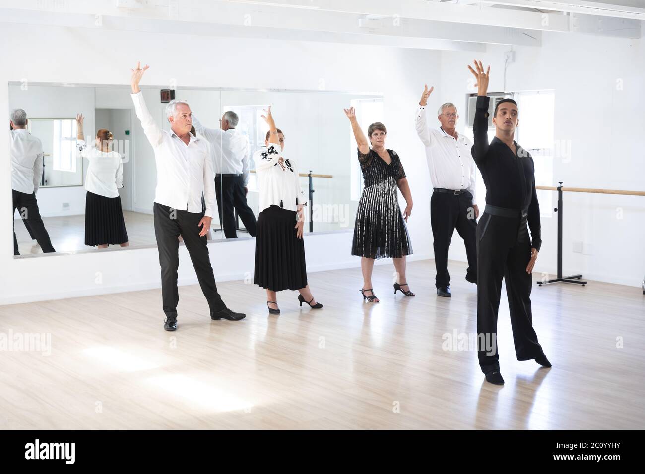 Mixed race dance teacher demonstrating to his ballroom dancing class